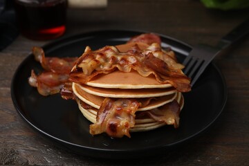 Delicious pancakes with fried bacon served on wooden table, closeup