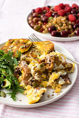 Healthy breakfast, scrambled eggs with fried seasonal forest mushrooms Chanterelles, salad with arugula, cucumbers and various seeds, fried zucchini pancakes with greens