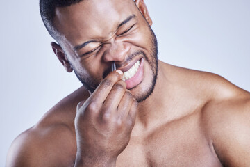 Black man, tweezers and nose grooming in studio, beauty and plucking for epilation on blue...
