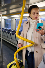 Woman with luggage checking phone while traveling on public transportation
