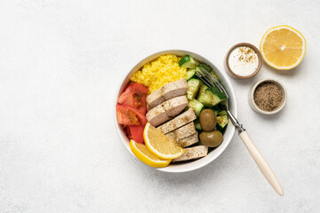 Healthy salad with chicken, tomato, cucumber, olives and rice in bowl on white background with copy space
