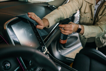 Naklejka premium A woman at a car wash does a full dry-cleaning of all parts of a car using special chemistry, cloths, sponges and brushes. Concept of: Full car cleaning, Dry cleaning, Professional service. Car, Work