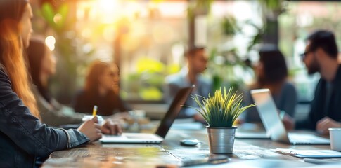 Team of business professionals in modern office space with laptops on table, soft focus effect image. Ideal for depicting teamwork, productivity and creative work environment