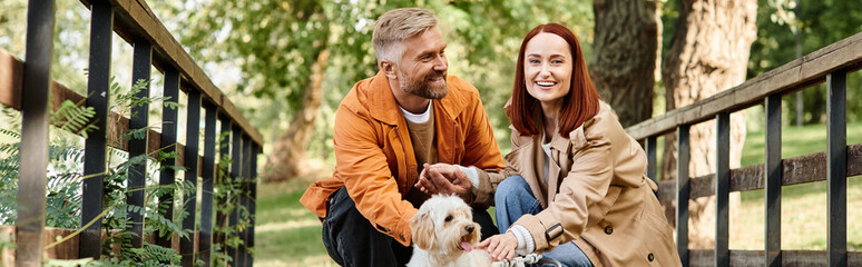 Adult couple enjoying a peaceful moment with their dog on a bridge.