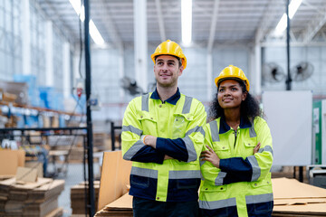 Male and female engineers in neat work clothes prepare and control the production system of large modern machines in a factory producing industrial technology products.