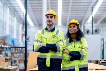 Male and female engineers in neat work clothes prepare and control the production system of large modern machines in a factory producing industrial technology products.
