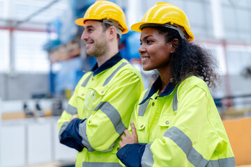 Male and female engineers in neat work clothes prepare and control the production system of large modern machines in a factory producing industrial technology products.