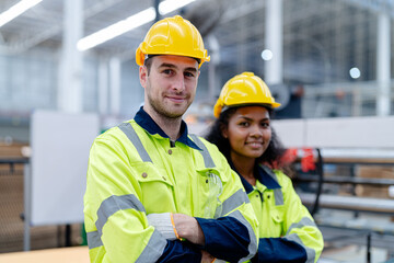 Male and female engineers in neat work clothes prepare and control the production system of large modern machines in a factory producing industrial technology products.