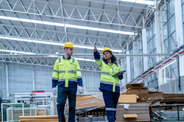 Male and female engineers in neat work clothes prepare and control the production system of large modern machines in a factory producing industrial technology products.