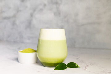 Refreshing matcha latte with powder or matcha with milk placed on white marble surface.  