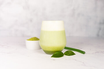 Refreshing matcha latte with powder or matcha with milk placed on white marble surface.  