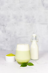 Refreshing matcha latte with powder or matcha with milk placed on white marble surface.  