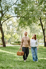 A couple, casually dressed, peacefully walking through a park.