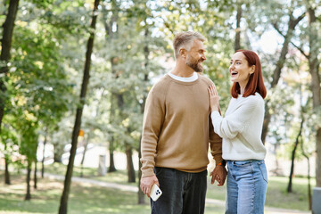 A man and a woman peacefully walk through a park.