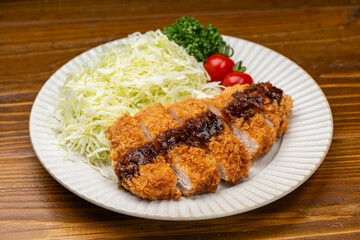 白い皿にソースのかかった豚カツと千切りキャベツ
