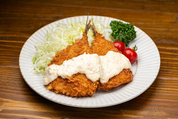 アジフライにタルタルソースをかけて食べる