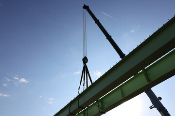 Large tonnage crane lifts a metal section of a bridge under construction.
