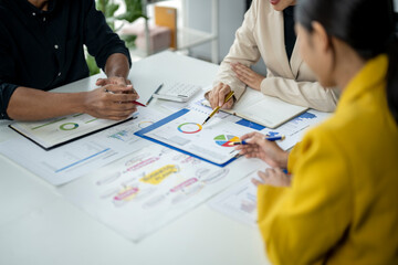 Three people are sitting at a table with papers and graphs in front of them