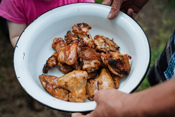 The image showcases someone serving a delicious plate of grilled chicken wings, known for their flavorful and aromatic qualities, providing a rich taste and texture experience