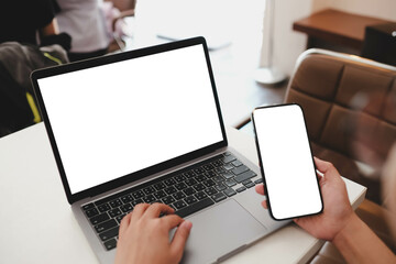 A woman Using Laptop and Smartphone with Blank Screens at a Café Table with Coffee shop.