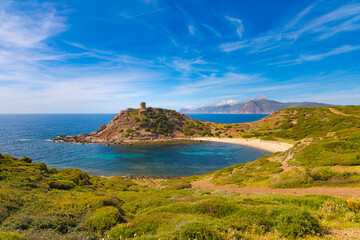 Fototapeta premium Torre Blanca de Porto Ferro en la costa noroeste de Cerdeña, Italia. La imagen muestra una pequeña bahía con aguas cristalinas rodeada de colinas verdes. 