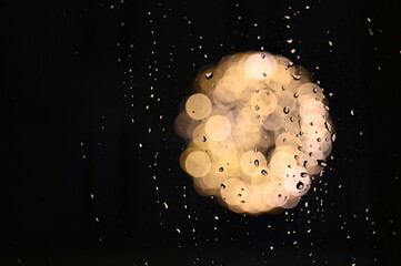 Gouttes de pluie  de nuit devant une forme lumineuse 