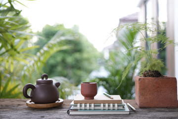 Tea cup and earthenware teapot and notebooks at the balcony and plant pot at balcony outdoor