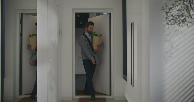 Handsome Caucasian male with beard entering home after work. buying groceries after leaving work. Going shopping before coming back to apartment. Happy man preparing to cook. Smiling with joy.