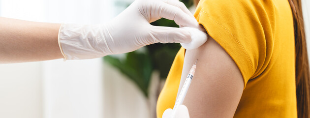 People getting a vaccination to prevent pandemic concept. Woman in medical face mask receiving a...