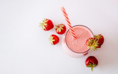 strawberry milkshake in a glass with a straw on a white background, top view