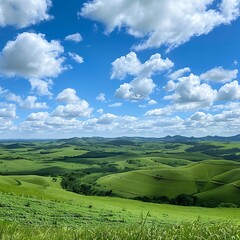 Obraz premium Panoramic view of rolling green hills under blue sky