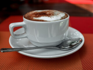 a cup of coffee in a white cup on an orange table. day.the sun. blurred background