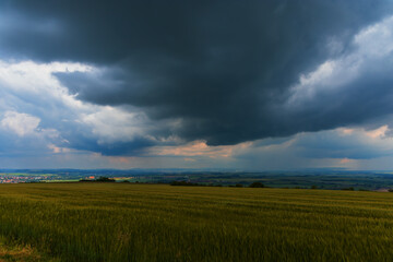 Spring fields with a view of the city. There are dramatic clouds in the sky.