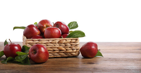 Fresh red apples and leaves in basket on wooden table against white background. Space for text
