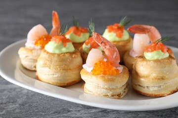 Different delicious puff pastry snacks on grey table