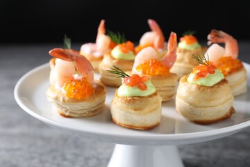Different delicious puff pastry snacks on grey table