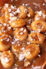 Tasty candies, caramel sauce and salt as background, closeup