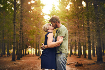 Couple, forest and happy with kiss for love with support, care and trust in Germany. People, relationship and affection in woods on holiday or vacation and travel for bonding, embrace and memories