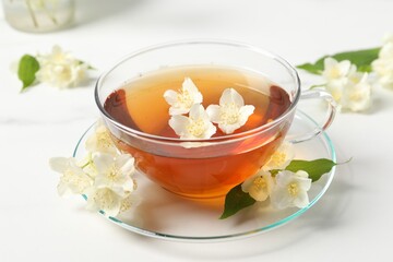 Hot jasmine tea in cup and flowers on white marble table