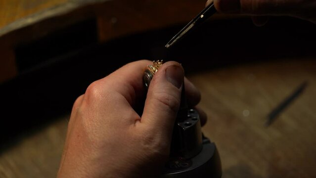 master of jewelry manually inserts gems into the frame of future jewelry. Working desk for craft jewelry making with professional tools. diamond ring on the jeweler's desktop