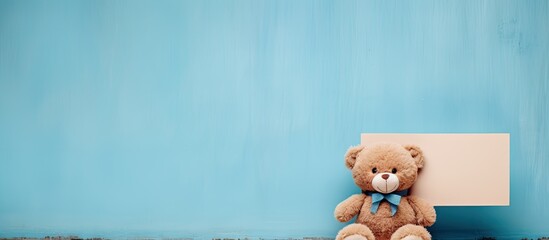 A cute teddy bear is positioned next to a blue wall featuring an empty label sign for customizable text. with copy space image. Place for adding text or design