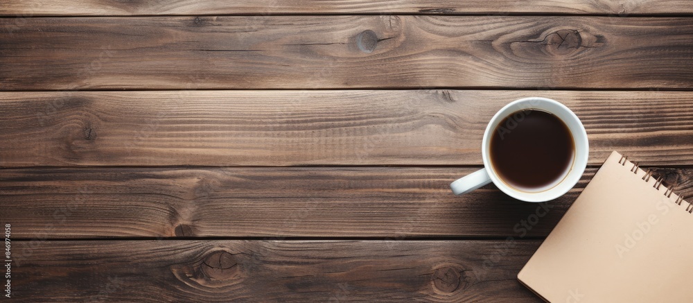Poster Coffee cup placed next to a notebook on a wooden tabletop, creating a cozy workspace. with copy space image. Place for adding text or design