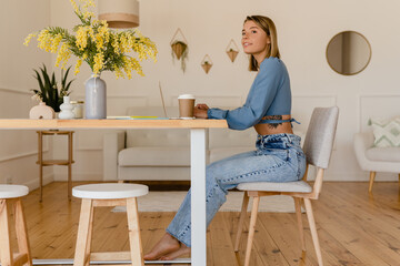 young pretty stylish woman working remote at home at table workplace, student education