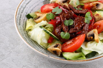 Asian beef salad with vegetables and nuts in a white bowl on a dark background. Asian food concept.