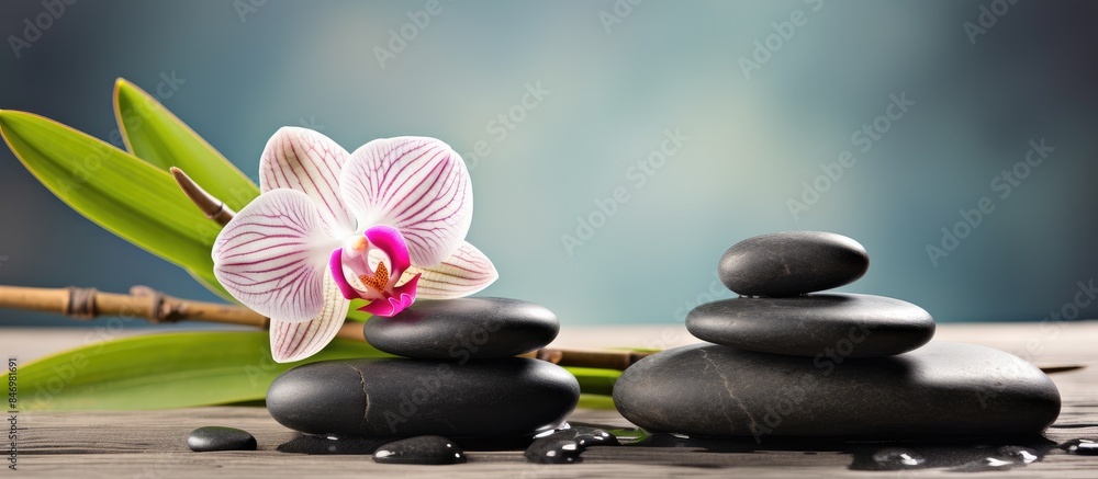 Aufkleber Zen stones and a delicate orchid placed on a wooden table creating a serene spa concept. with copy space image. Place for adding text or design