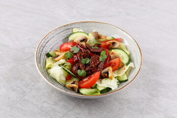 Asian beef salad with vegetables and nuts in a white bowl on a dark background. Asian food concept.