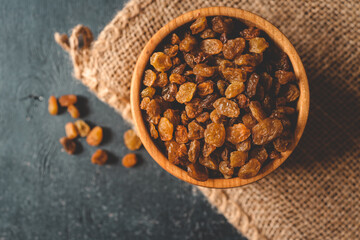 Golden dried raisins in wooden bowl on a wooden table