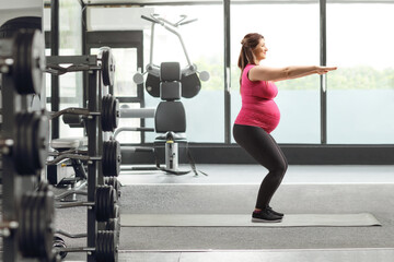 Fototapeta premium Pregnant woman exercising squats at a gym