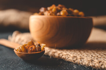 Golden dried raisins in wooden bowl on a wooden table