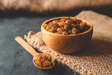 Golden dried raisins in wooden bowl on a wooden table